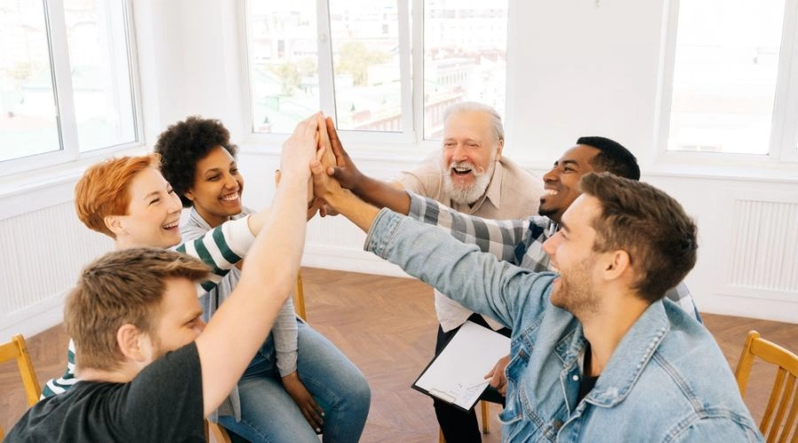 Group of six high fiving each other and celebrating their recovery