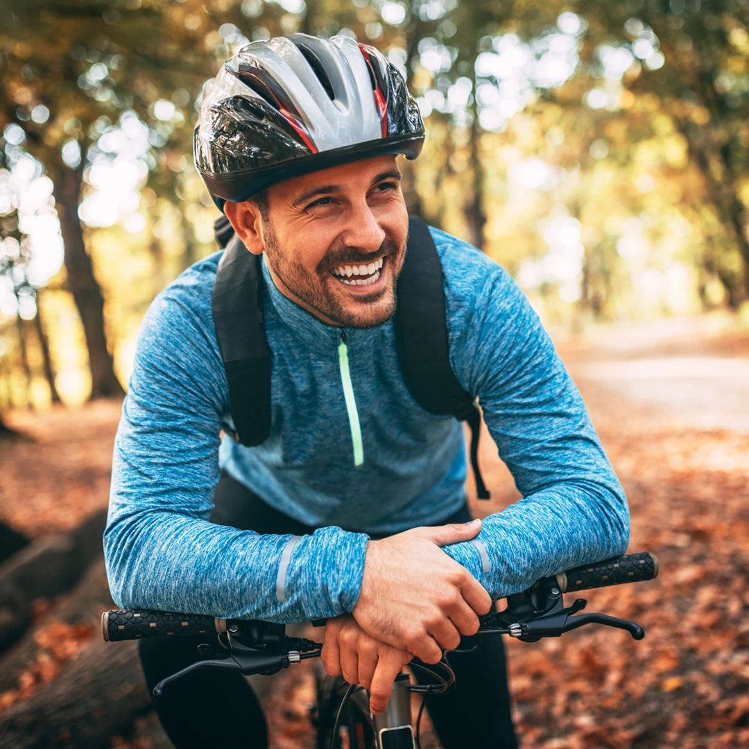 Smiling man on a bicycle wearing a helmet in a sunlit park—symbolizing active recovery and Mercy Care–covered mental and behavioral health services at Changes Healing Center in Arizona.