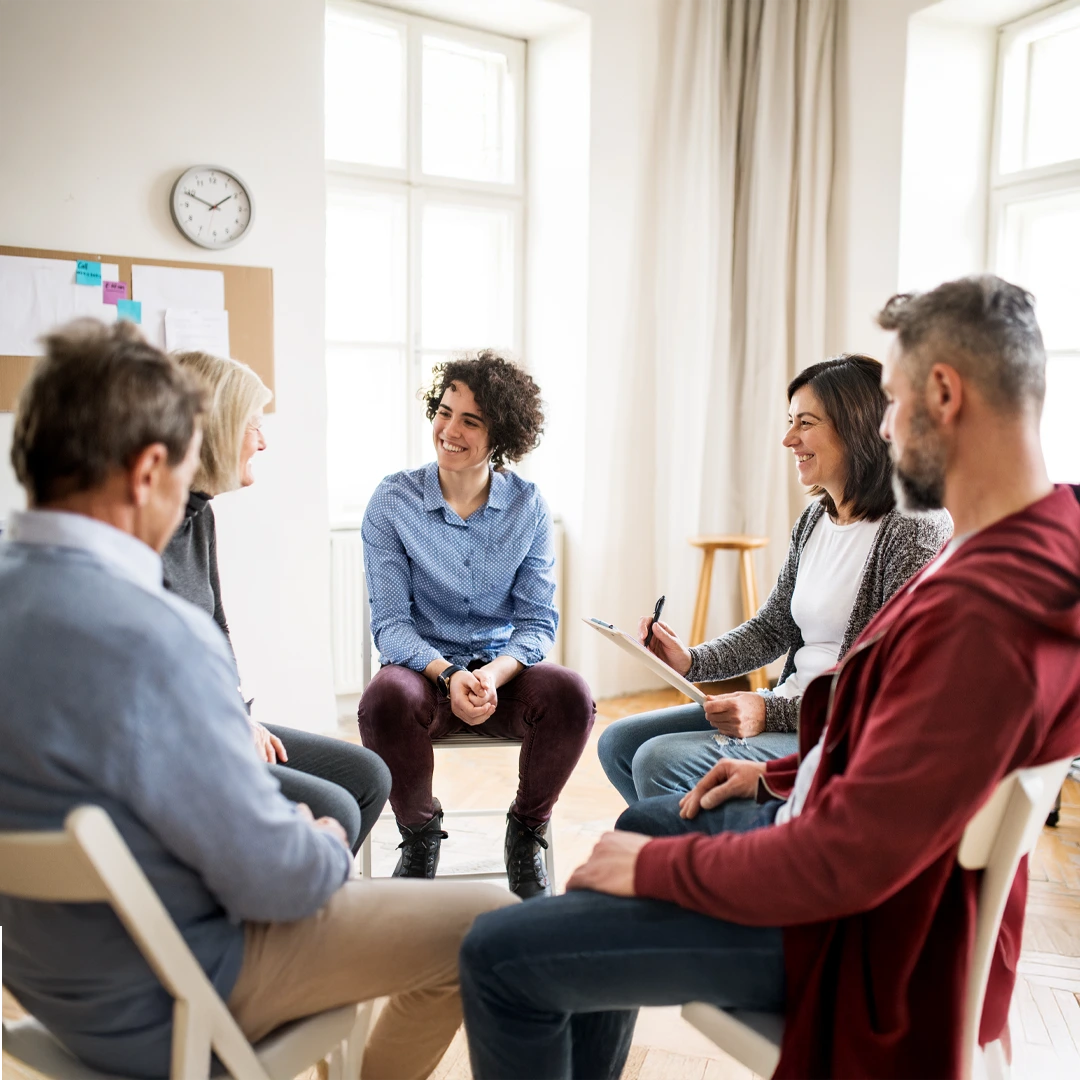 Small therapy group talking with a counselor in a bright room—compassionate addiction and mental health treatment in Phoenix–Scottsdale, AZ.