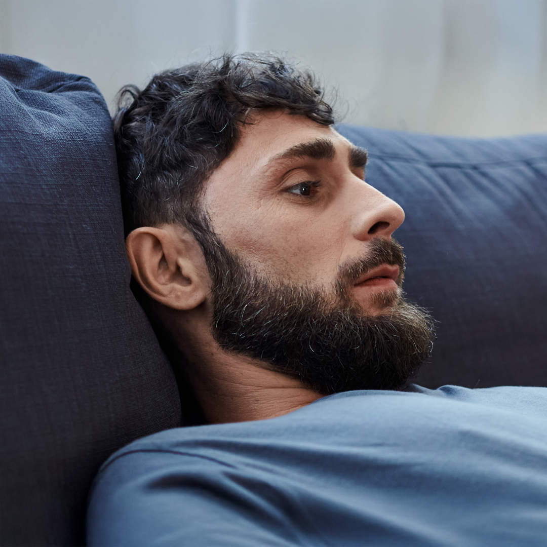 Man lying on couch in deep thought, representing the emotional and physical challenges of fentanyl addiction and the need for professional treatment in Phoenix, Arizona.