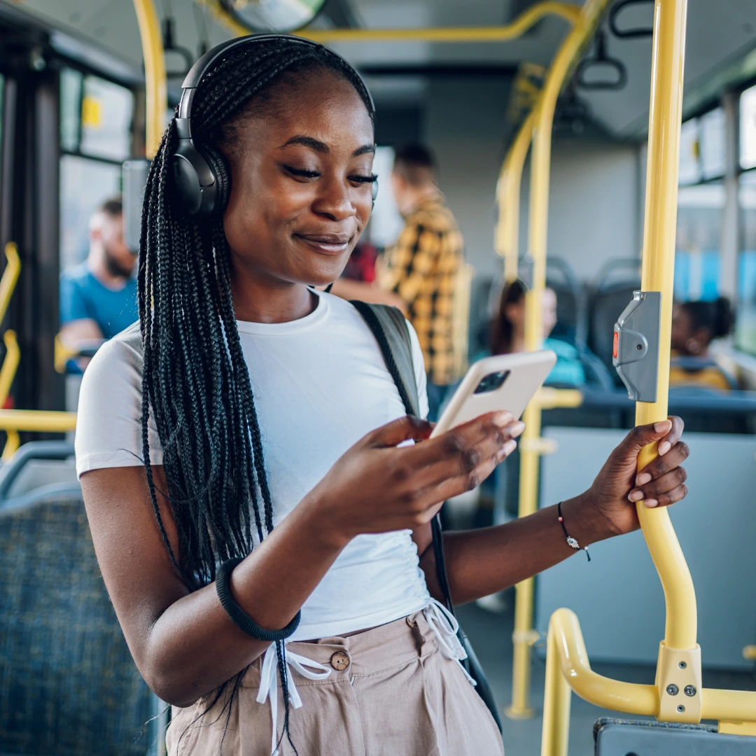 Young woman on a bus checking her phone—accessing mental health care covered by insurance.