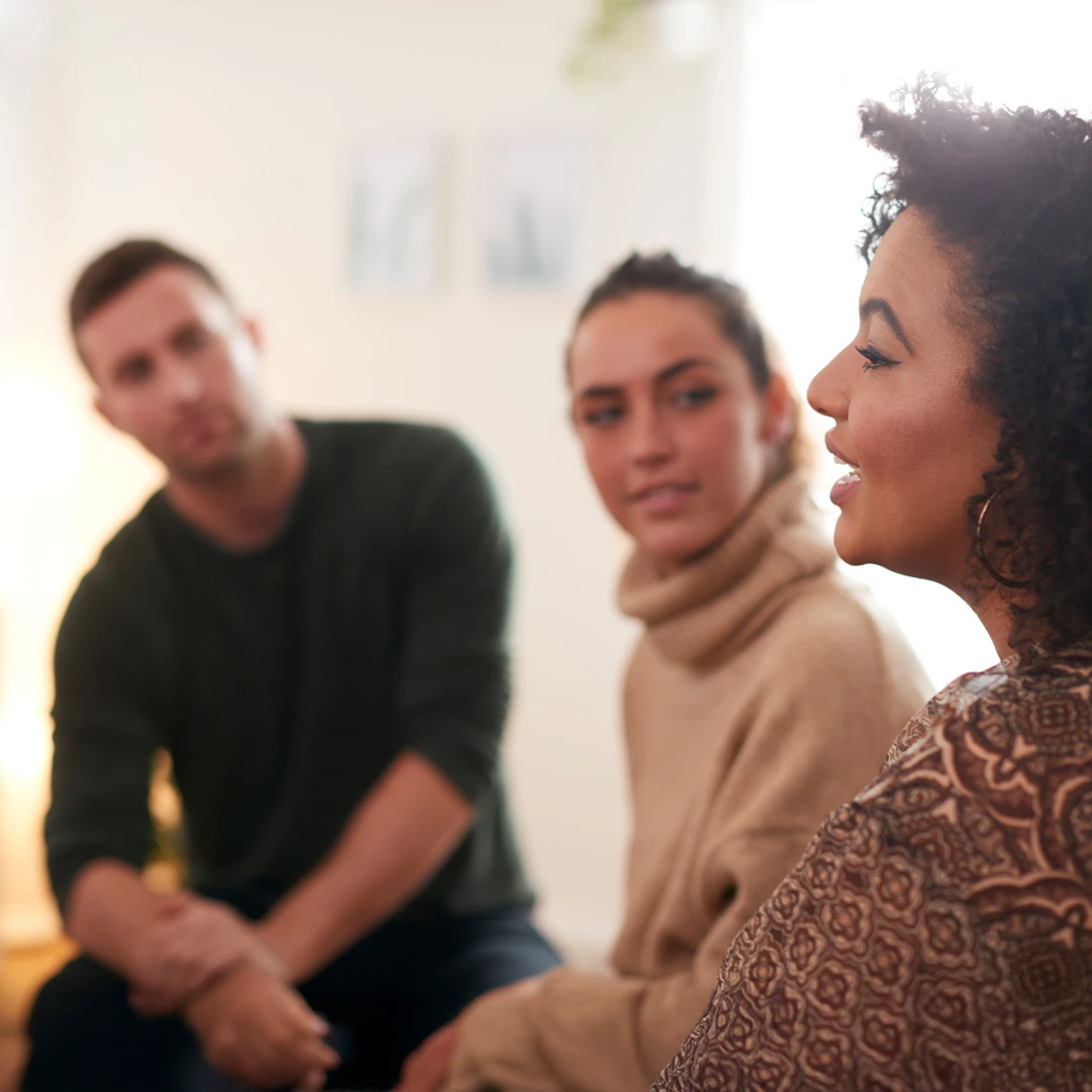 Adults in a small group conversation; one woman speaks while others listen—reflecting a welcoming, judgment-free admissions process at Changes Healing Center.