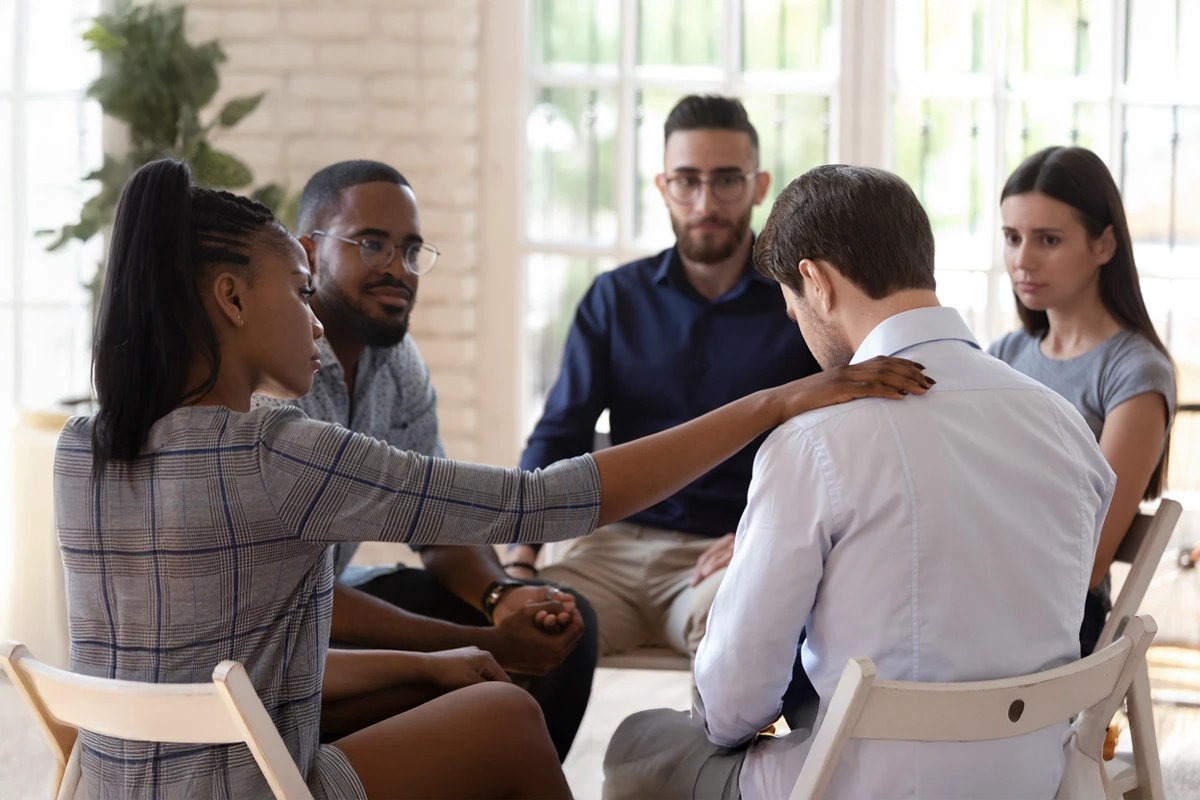 Trauma-informed group therapy; one participant gently comforts another during addiction and mental health treatment in Phoenix–Scottsdale, AZ.