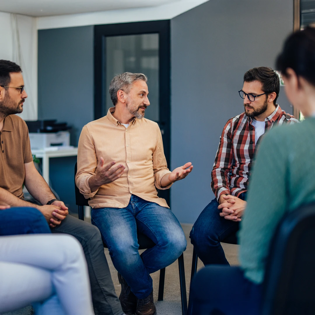 Adults in a supportive group therapy session at an Arizona Intensive Outpatient Program (IOP) discussing recovery.