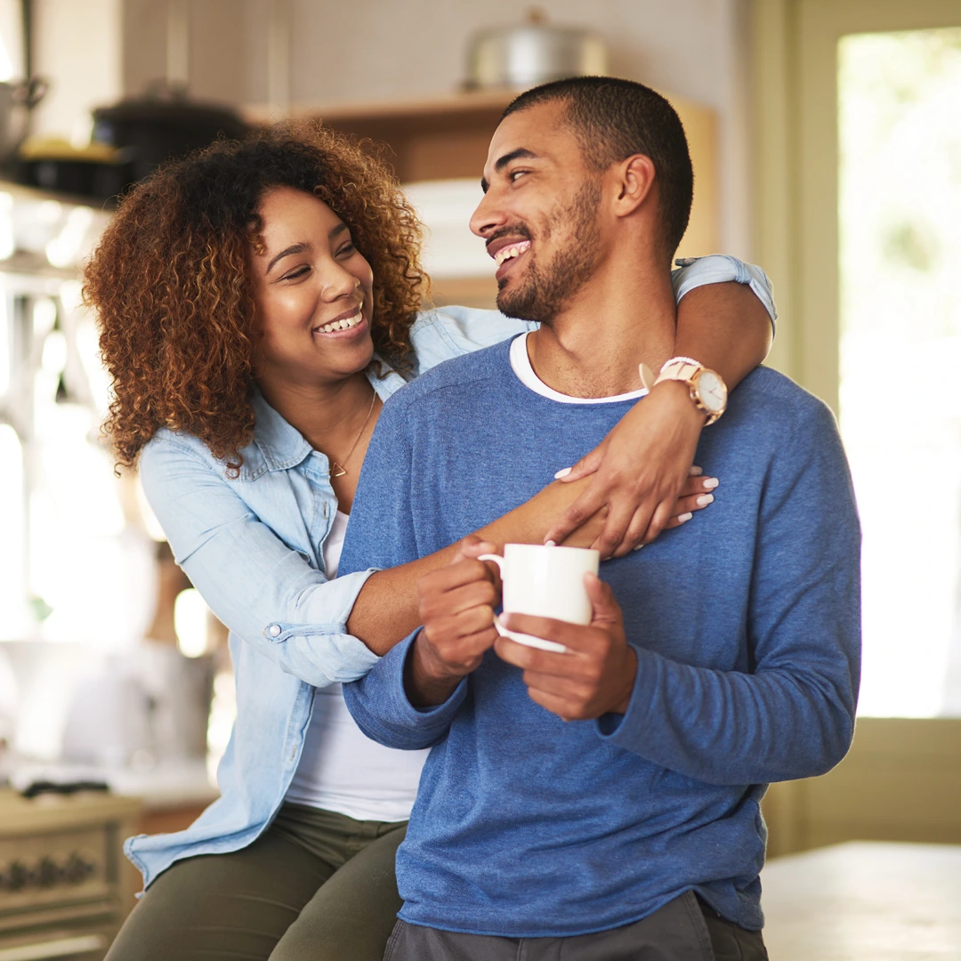 united-healthcare-drug-and-alcohol-coverage-couple-at-home-arizona-changes-healing-center Smiling couple embraces in a bright kitchen as one holds a coffee mug, reflecting support during recovery with UnitedHealthcare coverage.