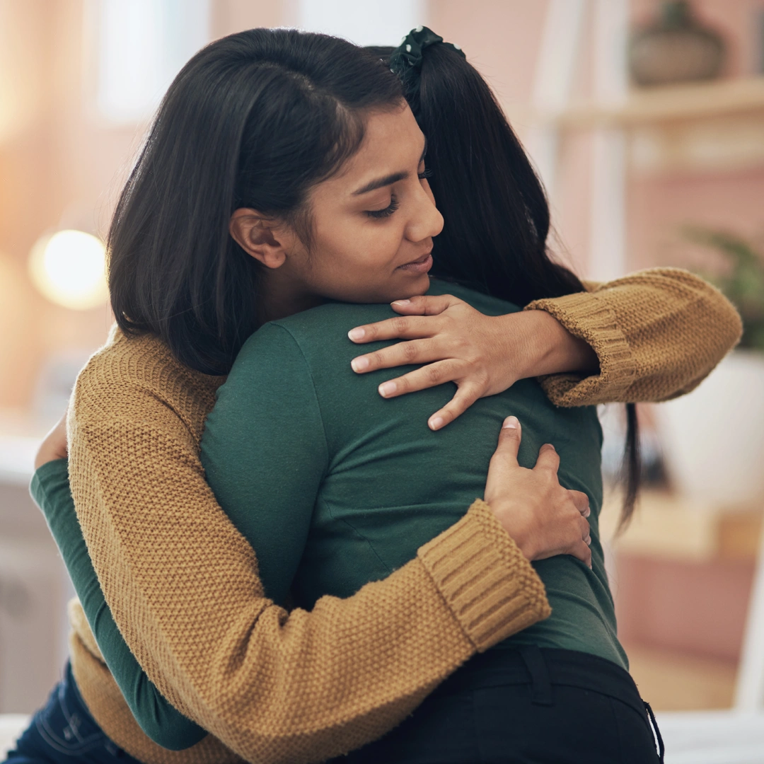 Two women embrace in a warm, comforting hug, symbolizing empathy, compassion, and emotional healing during a time of grief.