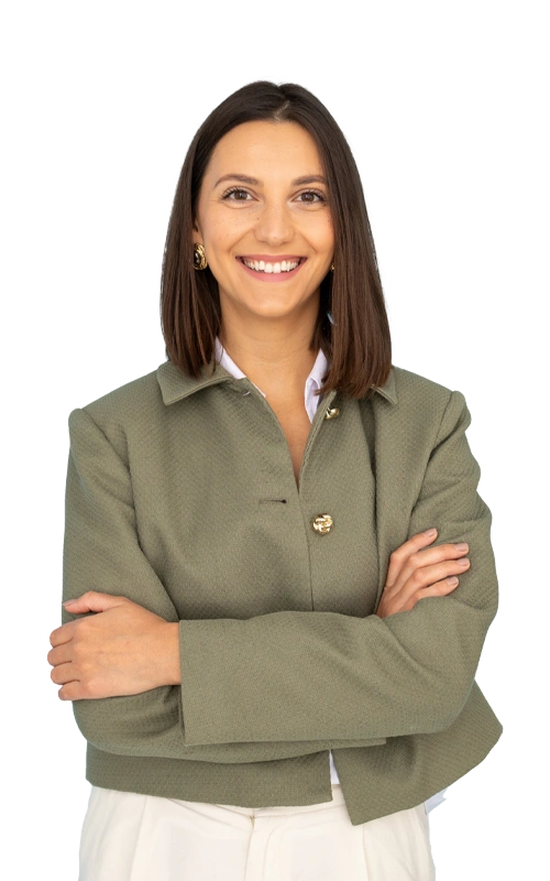 Smiling woman standing with arms crossed, wearing a green jacket and white shirt, representing confidence and support during PTSD recovery.