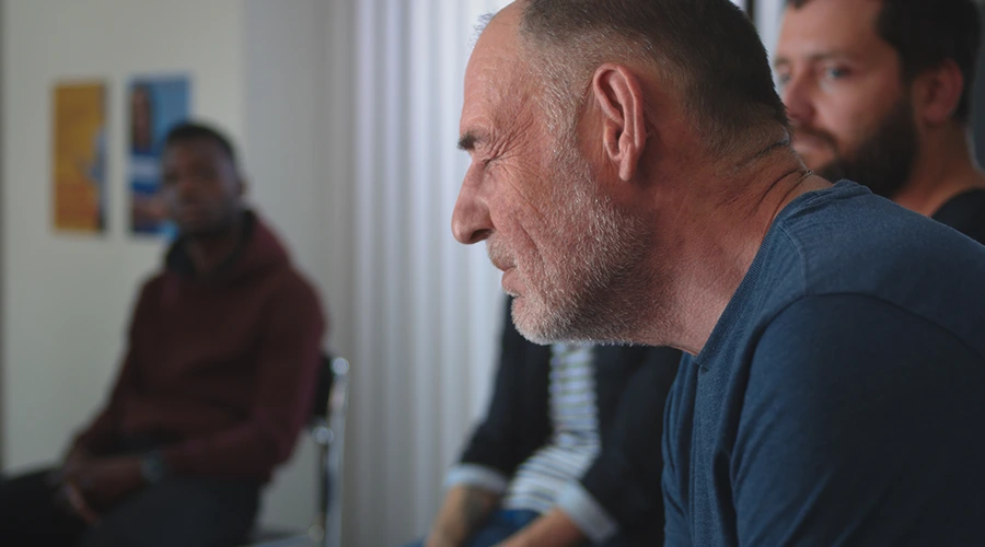 can-you-die-from-alcohol-withdrawal–900×500-changes-healing-center Man seated in a group therapy session listening during an alcohol addiction recovery meeting.